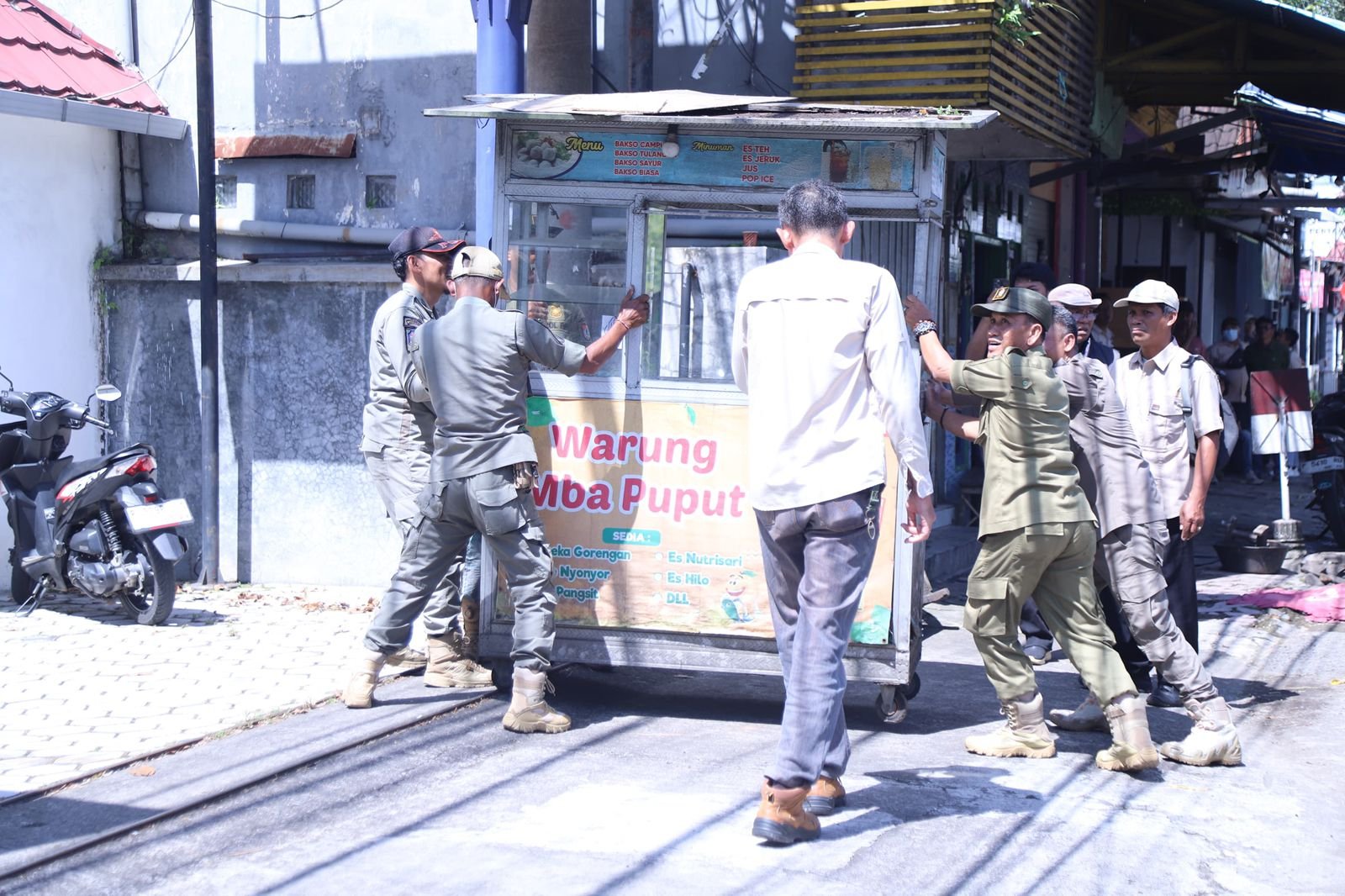 Satpol PP menertibkan rombong milik pedagang.