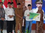 Bupati Mojokerto Muhammad Albarraa menyerahkan secara simbolis kepesertaan BPJS Ketenagakerjaan kepada guru TPQ dan Madin.
