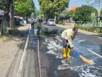 Petugas Damkar BPBD Jombang membersihkan tumpahan oli di Jalan KH Wahab Chasbullah, Desa Sambong Dukuh.(istimewa)