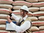 Dirut Bulog Ahmad Rizal Ramdhani meninjau gudang berisi tumpukan beras.