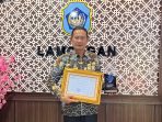 Bupati Lamongan Yuhronur Efendi menunjukkan piagam penghargaan.