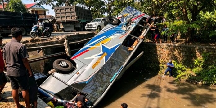 Bus Sugeng Rahayu yang terbalik ke dalam sungai di Dusun Kandangrejo, Desa Paron, Kecamatan Bagor, Nganjuk, setelah terlibat kecelakaan