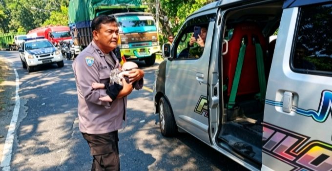 Aipda Sutrisno, Bhabinkamtibmas Polsek Bagor, dengan wajah panik saat menggendong dan melarikan bayi yang selamat dari bus tercebur sungai ke dalam ambulans di Jembatan Paron, Nganjuk
