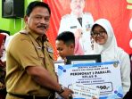 IMG-20260707-WA0012 Bupati Nganjuk Marhaen Djumadi menyerahkan beasiswa saat peluncuran Perpustakaan Digital "Pustaka Cendekia ARPEDA" di SMP Negeri 2 Nganjuk