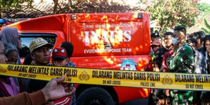 Petugas memasang police line di lokasi penemuan jenazah Gatot di Dusun Nanggungan, Desa Kaloran, Kecamatan Ngronggot (Agus Karyono)