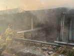 Petugas Damkar memadamkab kebakaran ruko akibat pembakaran sampah di Jalan Raya Pasar Dukun, Gresik.