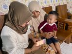 Lik Astutik bersama anak dan cucunya saat memanfaatkan aplikasi Mobile JKN. (Foto: Andika DP)