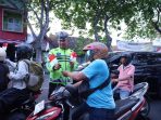 Anggota Satlantas Polres Gresik membagikan bendera Merah Putih kepada pengendara.