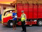 Petugas Satlantas Polres Nganjuk saat menghentikan dan memberikan sanksi tilang kepada pengemudi truk pengangkut padi yang nekat membawa penumpang di atas tumpukan muatan.