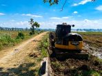 Satu unit alat berat excavator milik Dinas PUPR Kabupaten Nganjuk mengeruk endapan lumpur dan material vegetasi di saluran tersier Desa Nglawak, Kecamatan Prambon