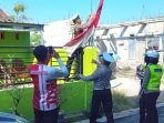 Personel Satlantas Polres Nganjuk bersama pemilik rumah mengganti bendera kusam dengan Bendera Merah Putih baru
