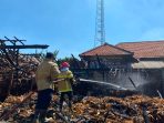 Petugas Damkar Gresik memadamkan kebakaran kandang kambing.