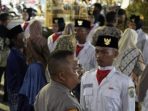 PS Kanit Pamapta Polsek Balongpanggang Aiptu Achmad Hadi Susanto menghampiri Gilang yang dikukuhkan sebagai anggota paskibra tanpa kehadiran orang tua. (Foto: Ist)