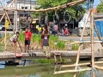Peserta lomba ala ninja warrior saat menaklukkan rintangan di atas Sungai Krembangan, Sidoarjo. (Foto: Achmad Adi Nurcahya)