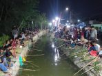 Warga berjejer memancing pakai joran bambu memperingati HUT ke-81 RI di Desa Singkalan, Sidoarjo. (Foto: Achmad Adi Nurcahya)
