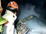 Petugas Damkarmat Kabupaten Nganjuk berjibaku menyemprotkan air untuk melokalisasi dan memadamkan kobaran api yang menghanguskan kandang ternak warga di Desa Ngumpul, Bagor, Nganjuk,
